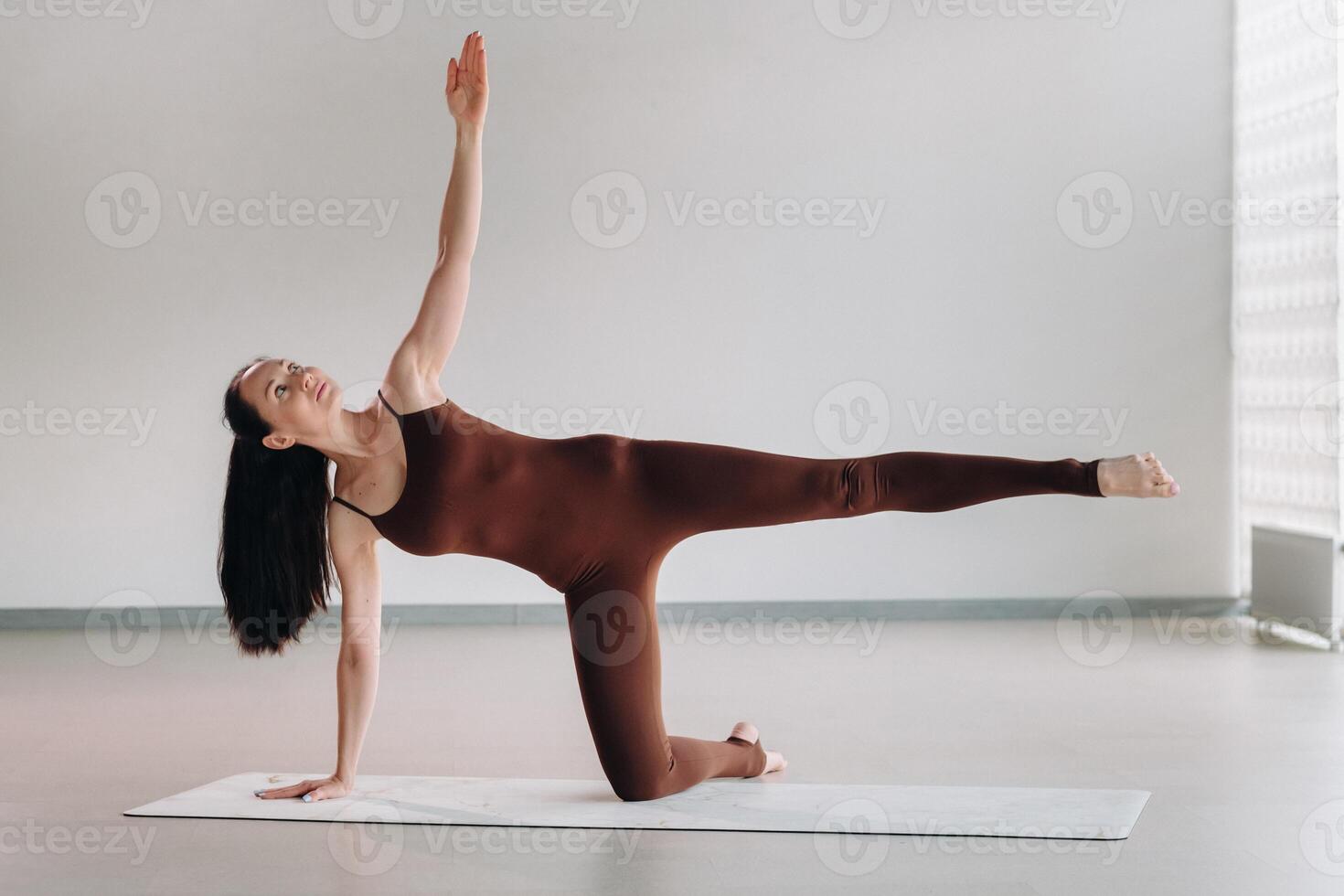 a woman in a brown suit does yoga in a fitness room . Healthy lifestyle, fitness, training, self-care photo
