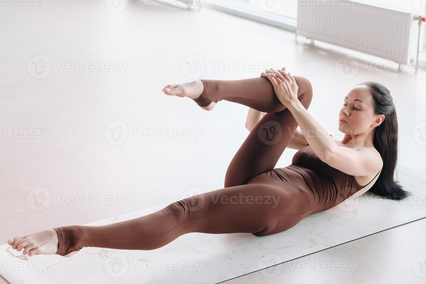 a woman in a brown suit does yoga in a fitness room . Healthy lifestyle, fitness, training, self-care photo