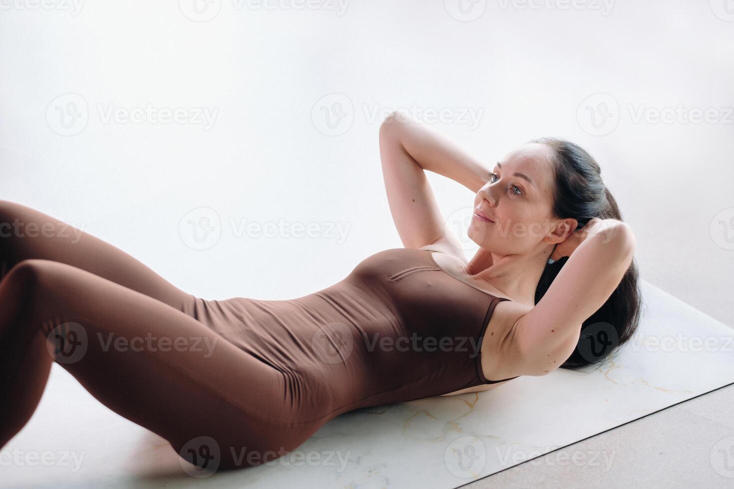 a woman in a brown suit does yoga in a fitness room . Healthy lifestyle, fitness, training, self-care photo
