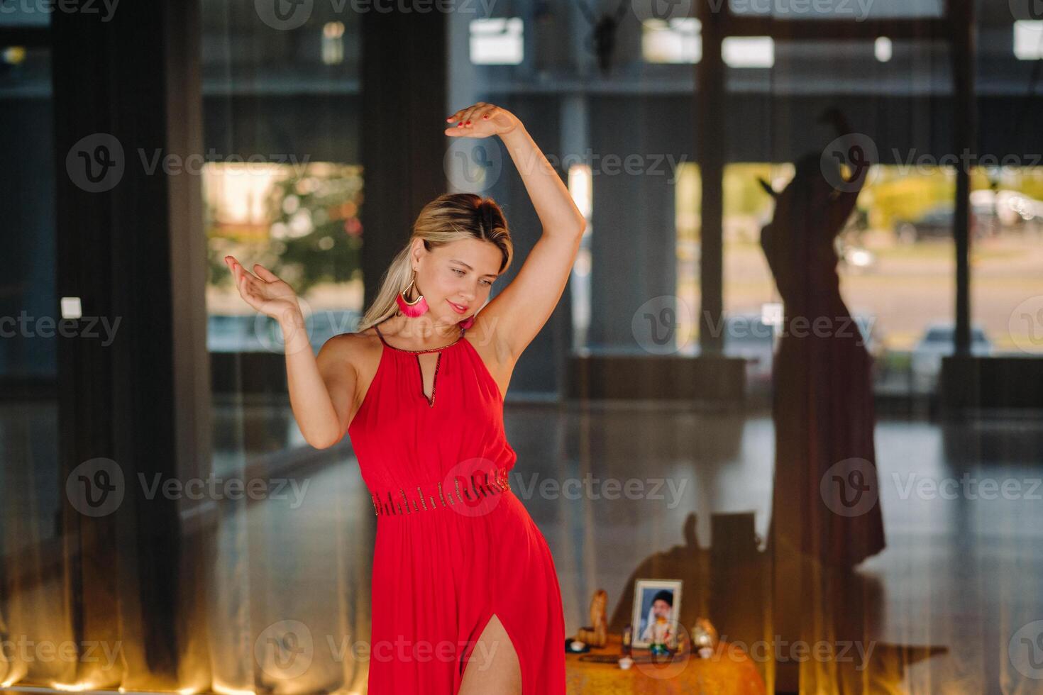 A girl in a red dress moves in a dance meditating indoors . Dynamic dance photo