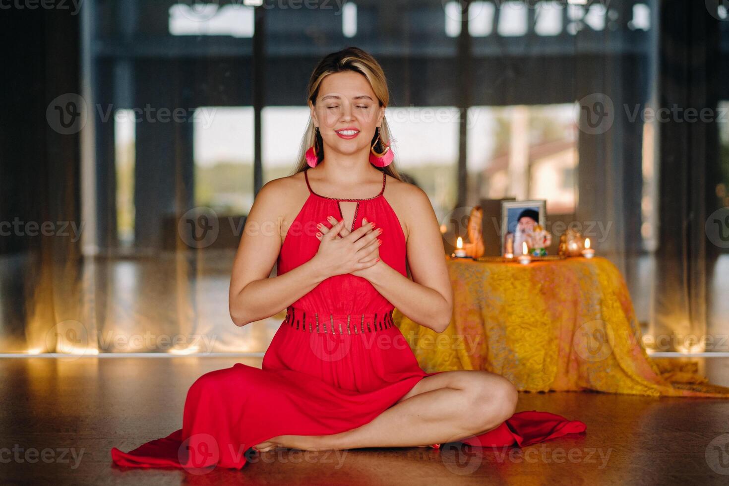Meditation and concentration. a woman in a red dress sitting on the floor is practicing medicine indoors . Calm and relaxation photo