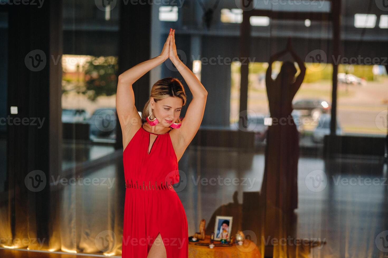 A girl in a red dress moves in a dance meditating indoors . Dynamic dance photo