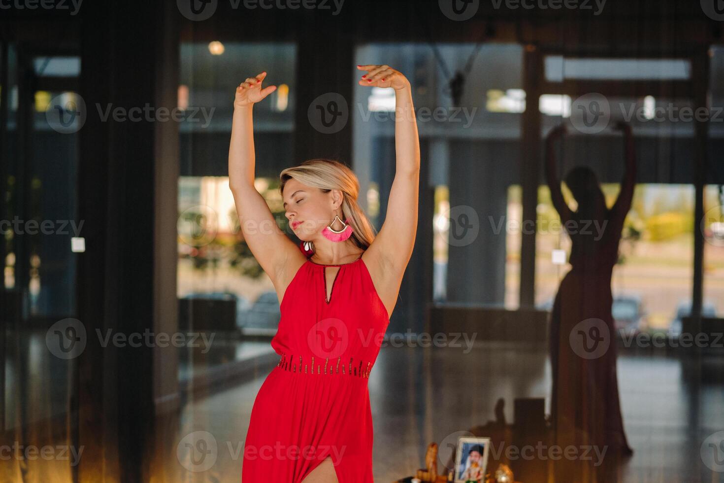 A girl in a red dress moves in a dance meditating indoors . Dynamic dance photo