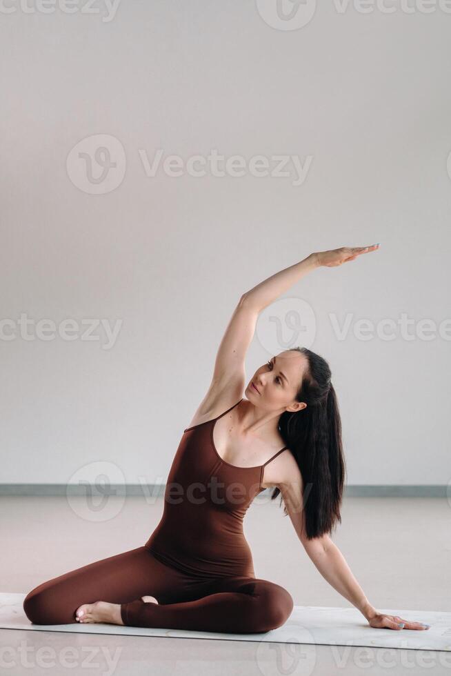 a woman in a brown suit does yoga in a fitness room . Healthy lifestyle, fitness, training, self-care photo