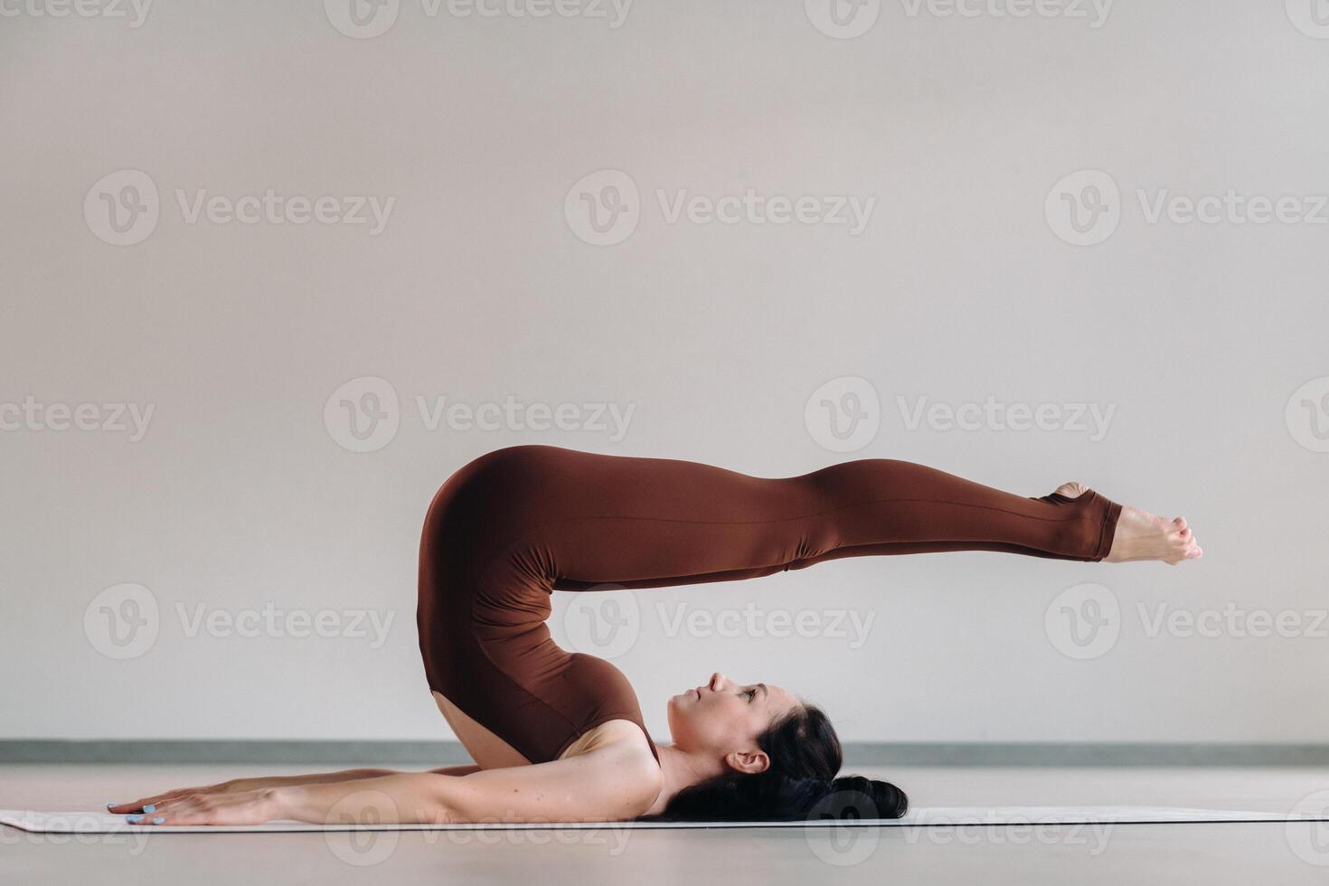 a woman in a brown suit does yoga in a fitness room . Healthy lifestyle, fitness, training, self-care photo