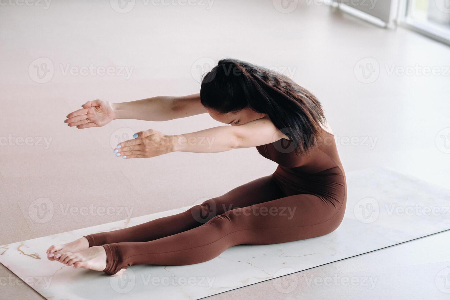 a woman in a brown suit does yoga in a fitness room . Healthy lifestyle, fitness, training, self-care photo