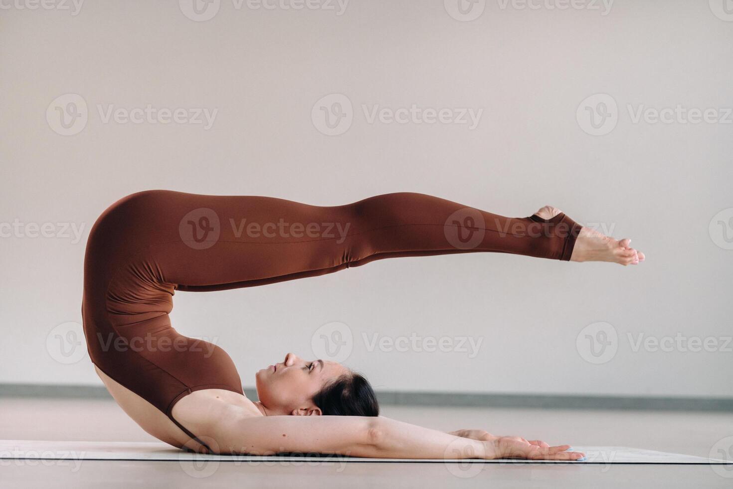a woman in a brown suit does yoga in a fitness room . Healthy lifestyle, fitness, training, self-care photo