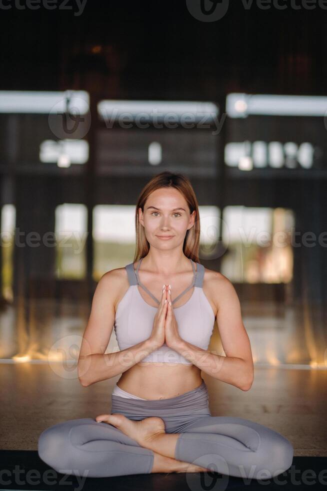 The girl does yoga. A woman in sports clothes does yoga exercises in the gym photo