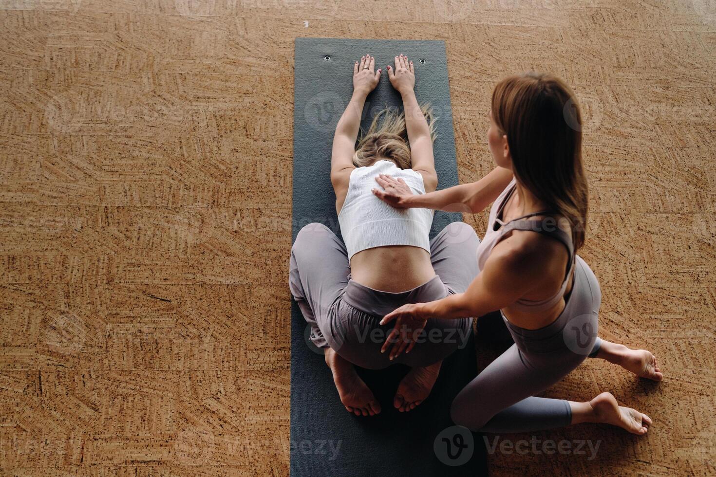 Yoga exercises. A personal trainer teaches a woman yoga classes in the gym photo