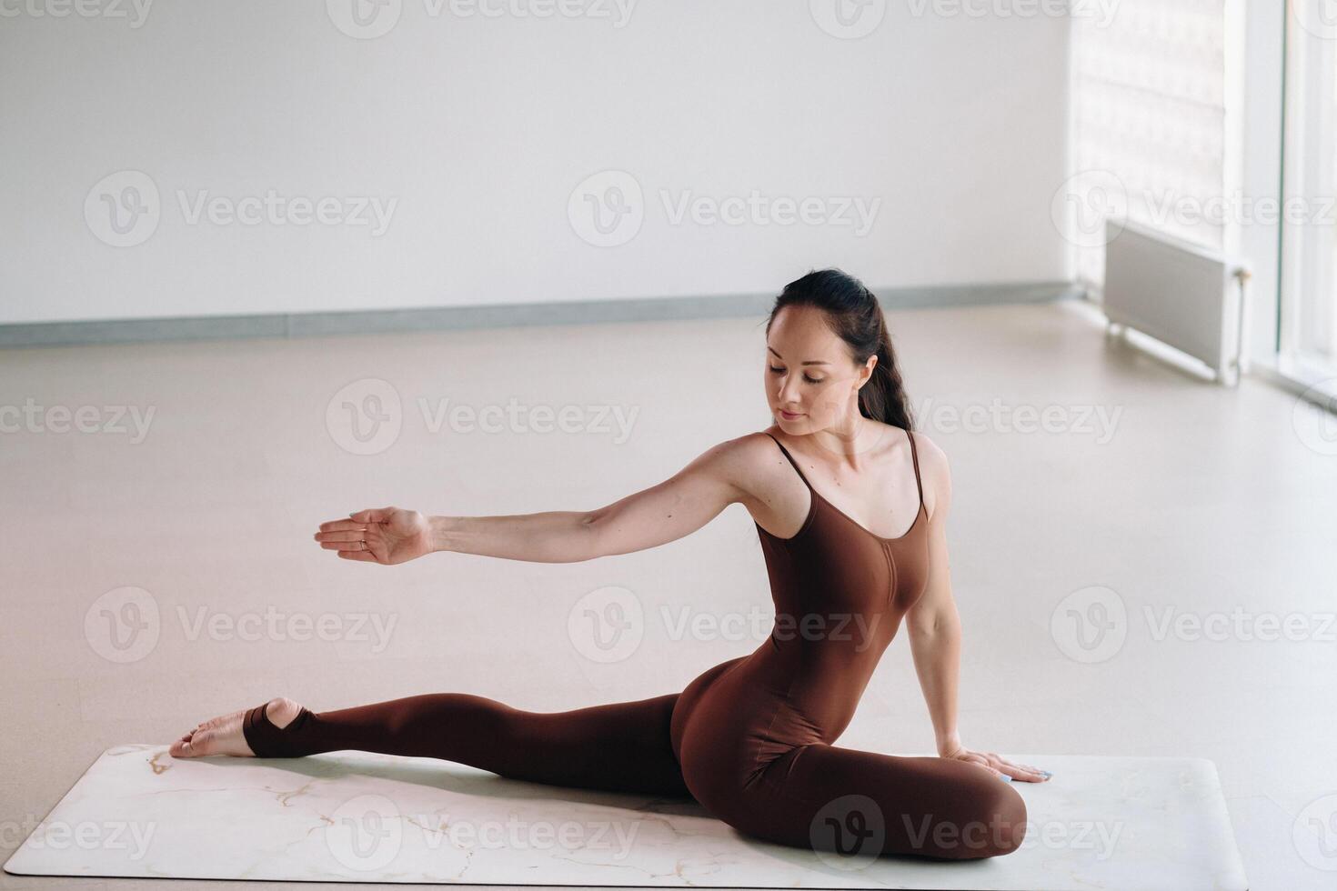 a woman in a brown suit does yoga in a fitness room . Healthy lifestyle, fitness, training, self-care photo
