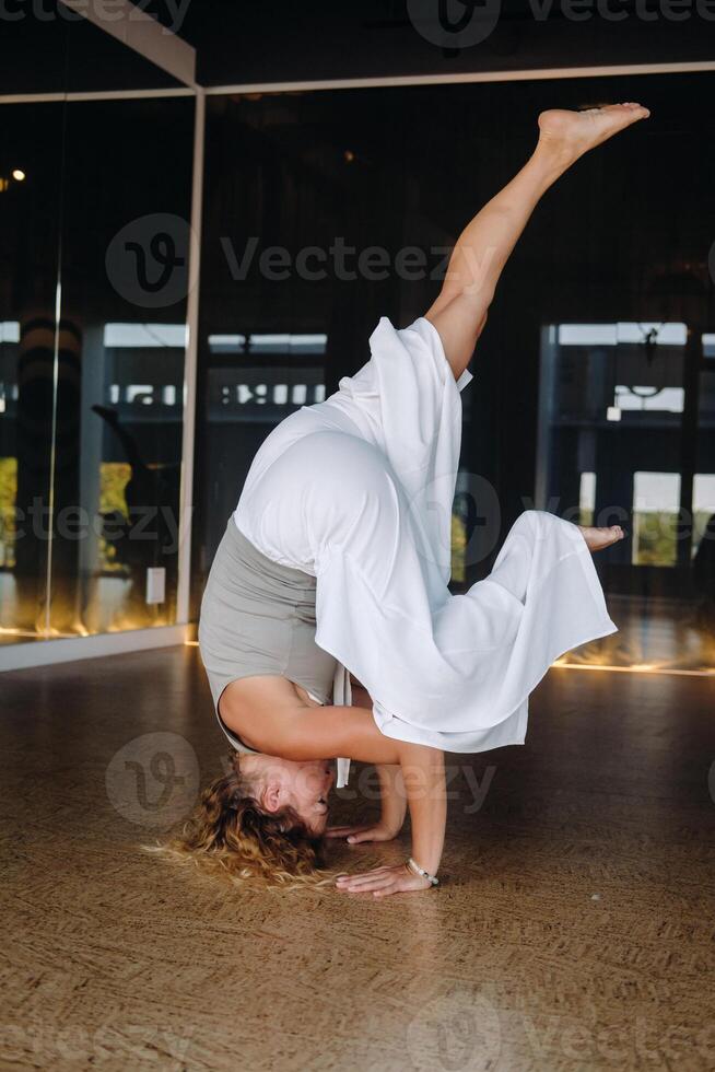 A woman Performing yoga exercises on her head in the gym photo