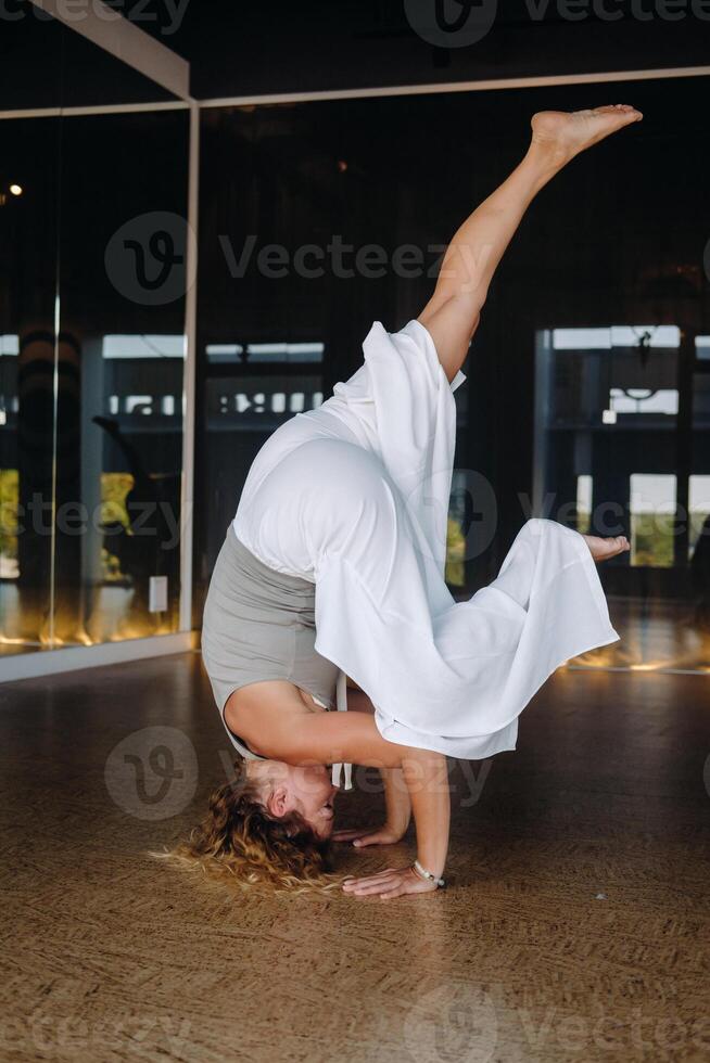 A woman Performing yoga exercises on her head in the gym photo