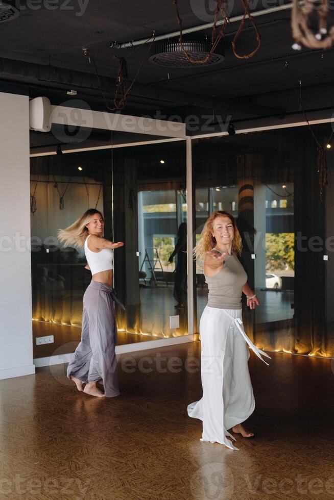 Two women in sportswear are doing dance yoga in the gym photo