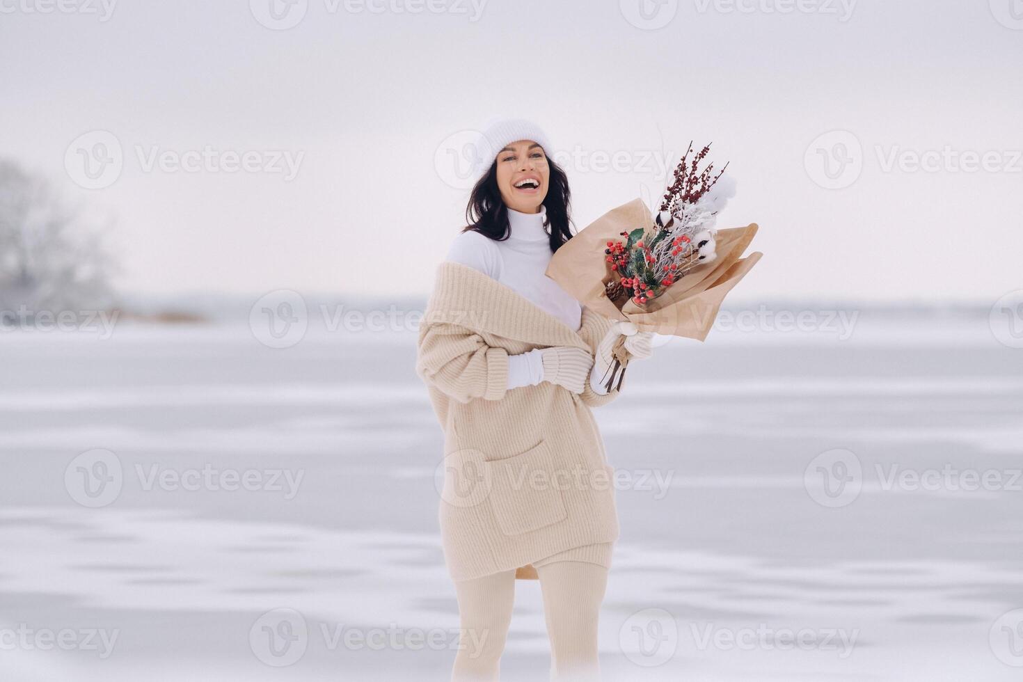 A girl in a beige cardigan and winter flowers walks in nature in the snowy season. Winter weather photo