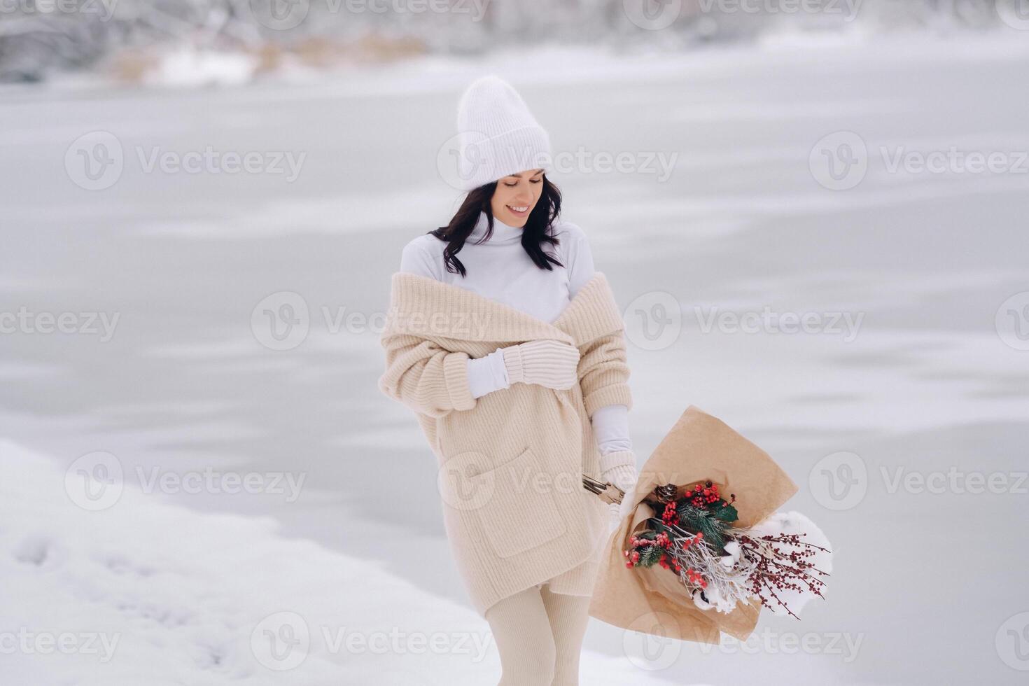 A girl in a beige cardigan and winter flowers walks in nature in the snowy season. Winter weather photo