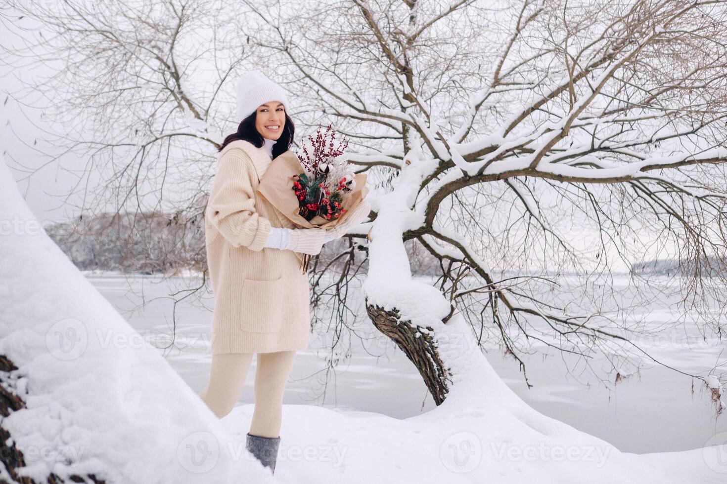 A girl in a beige cardigan and winter flowers walks in nature in the snowy season. Winter weather photo