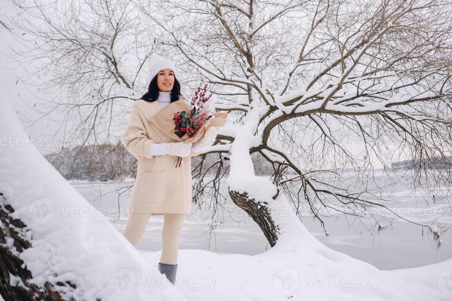 A girl in a beige cardigan and winter flowers walks in nature in the snowy season. Winter weather photo