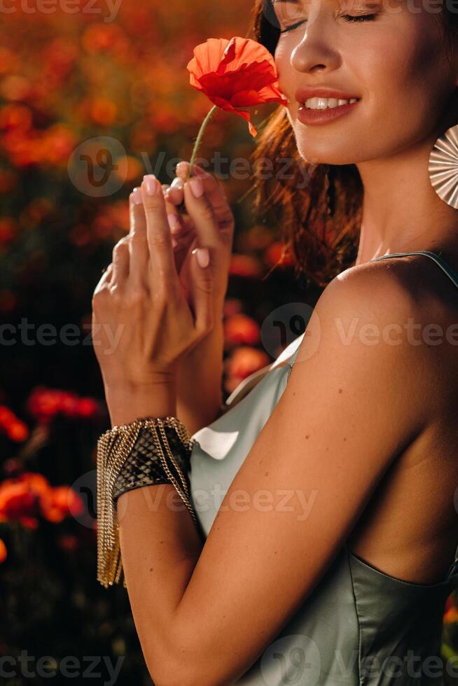 Portrait of a girl in a dress on a poppy field at sunset photo