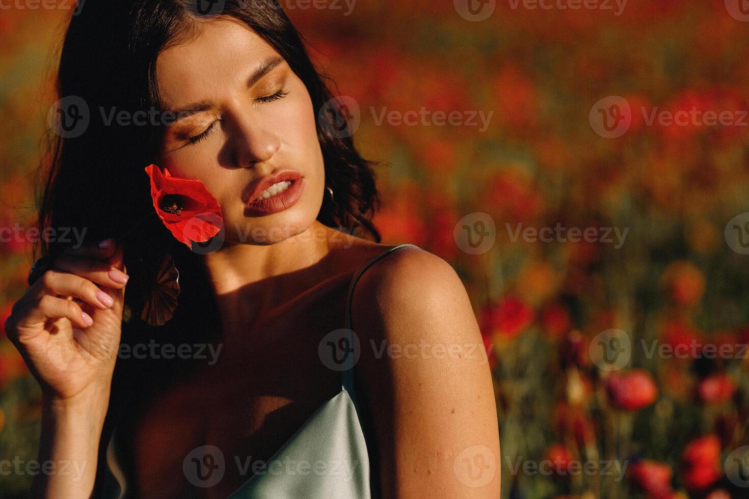 Portrait of a girl in a dress on a poppy field at sunset photo