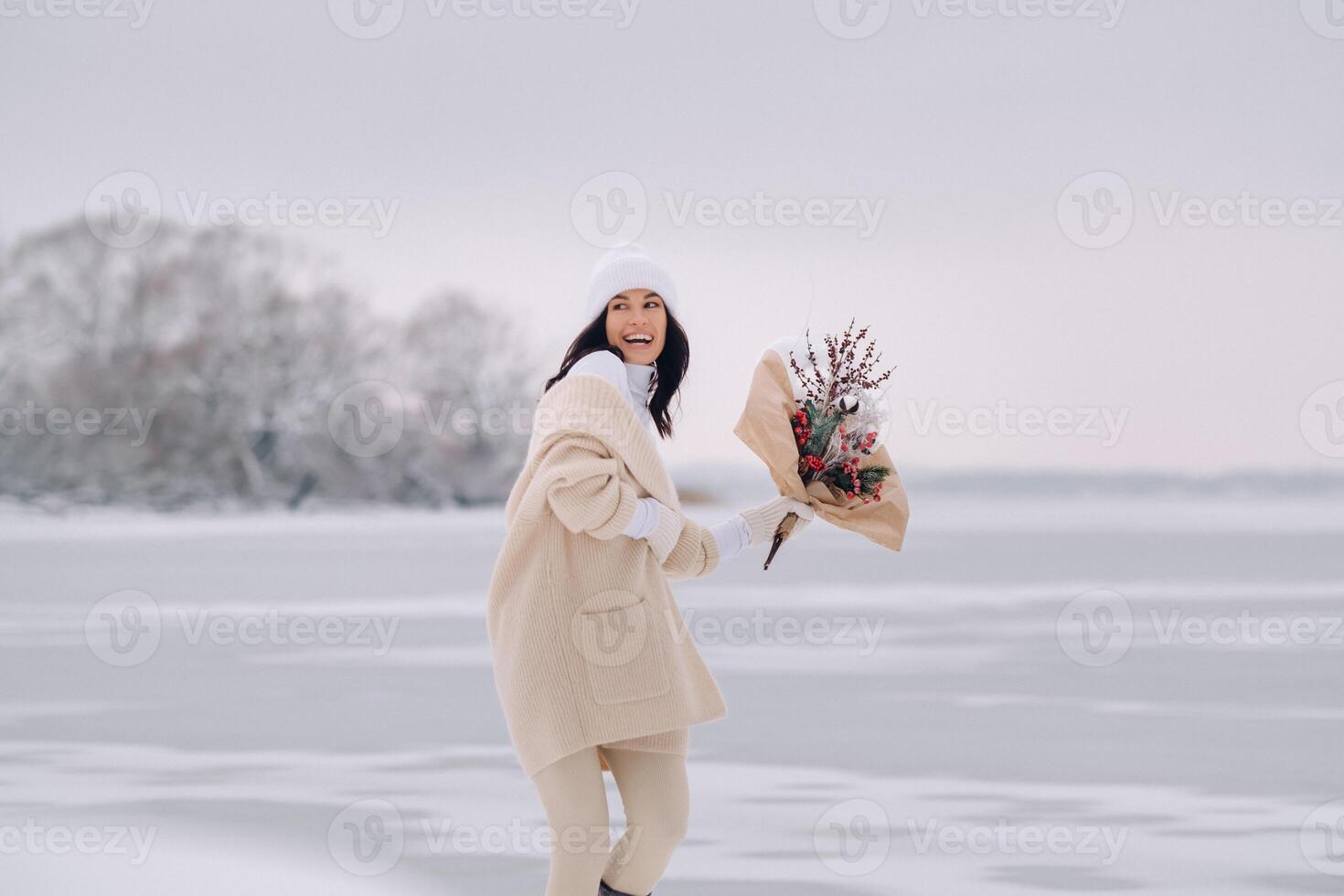 A girl in a beige cardigan and winter flowers walks in nature in the snowy season. Winter weather photo