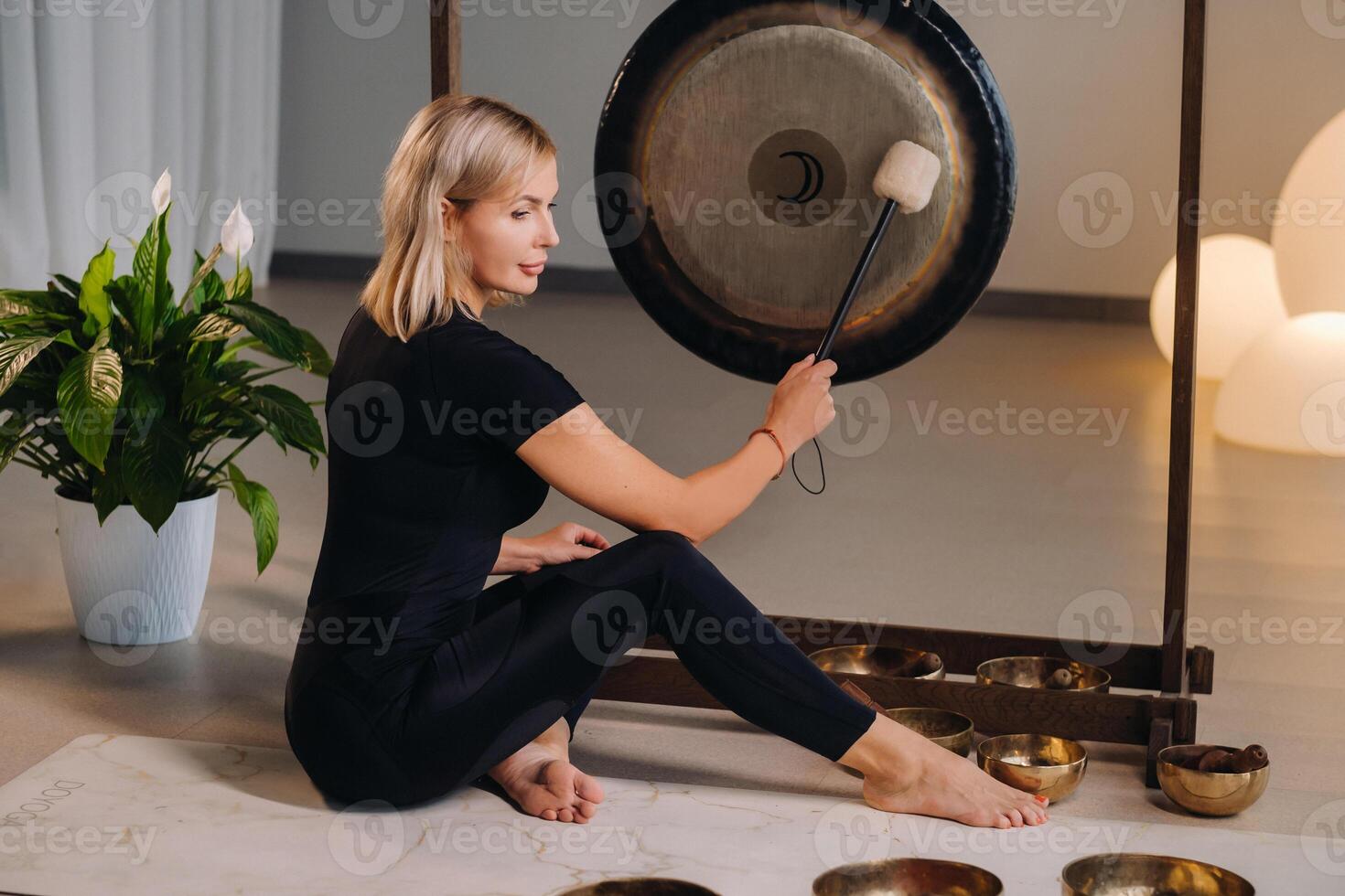 A woman knocks a mallet with a hammer on a gong. A gong and a hand beater for the gong photo