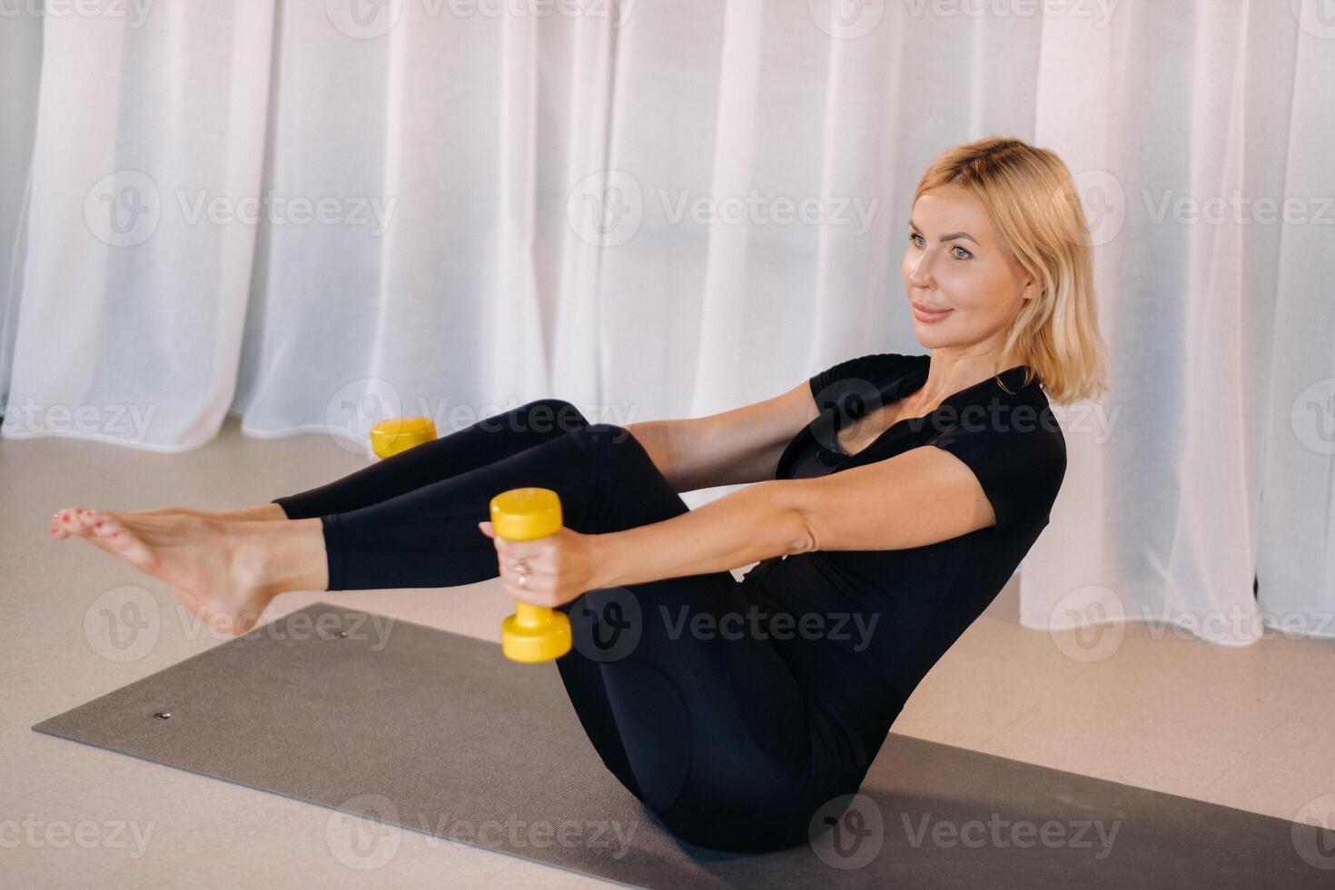 a woman in black sportswear is doing fitness with dumbbells in her hands. Sports, health, gymnastics and lifestyle concept photo