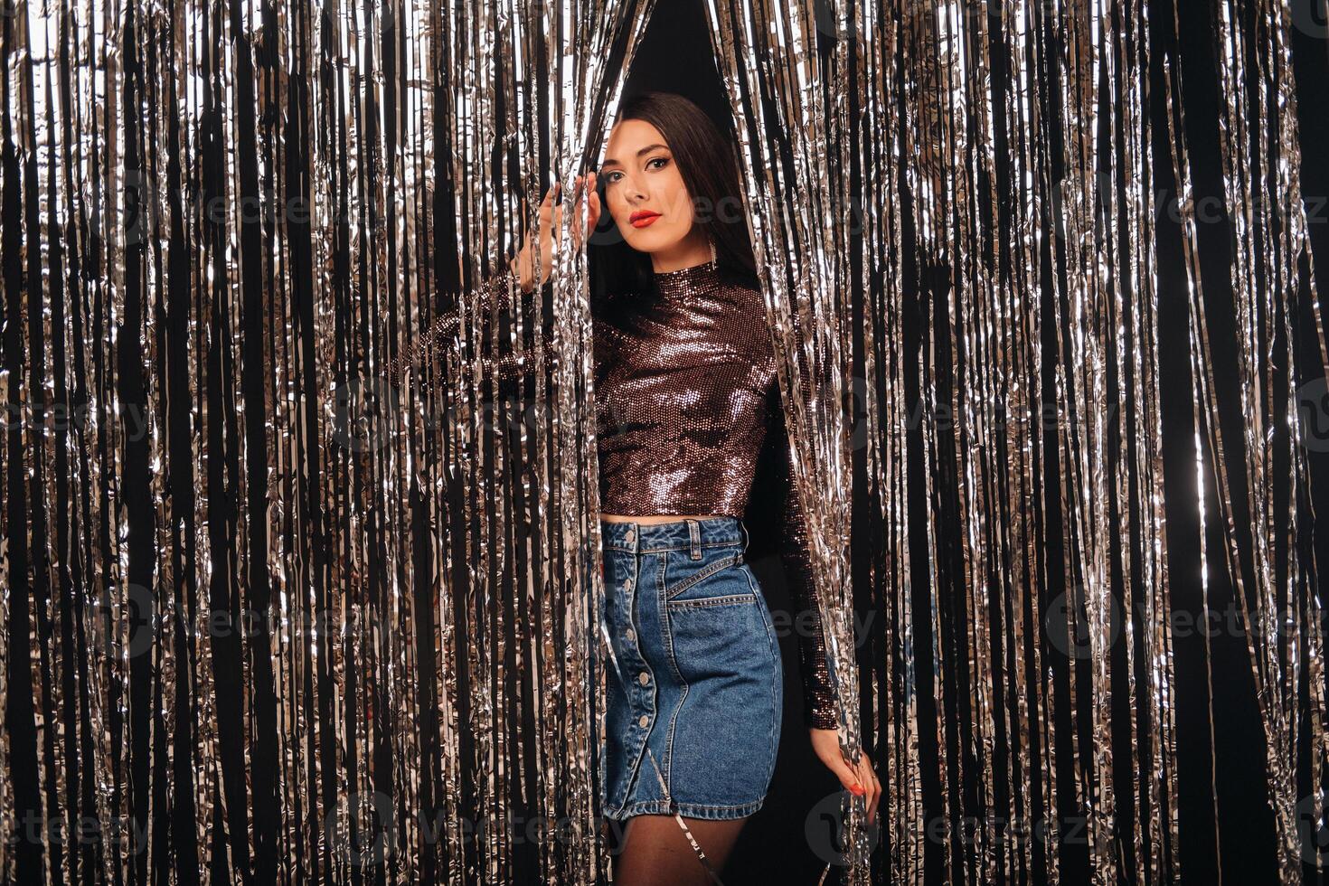 a girl in a shiny jacket on a silver background of New Year's rain photo