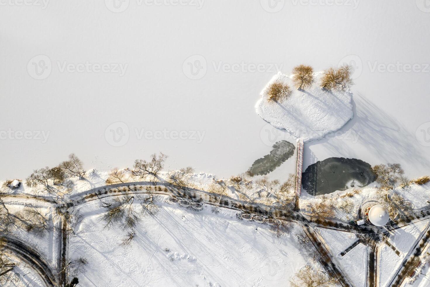 an island on a lake with a bridge in the Winter Loshitsky Park. Minsk, Belarus photo