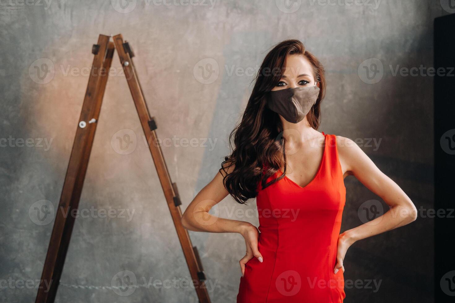 Glamorous girl in a red dress and a protective mask on a vintage background photo