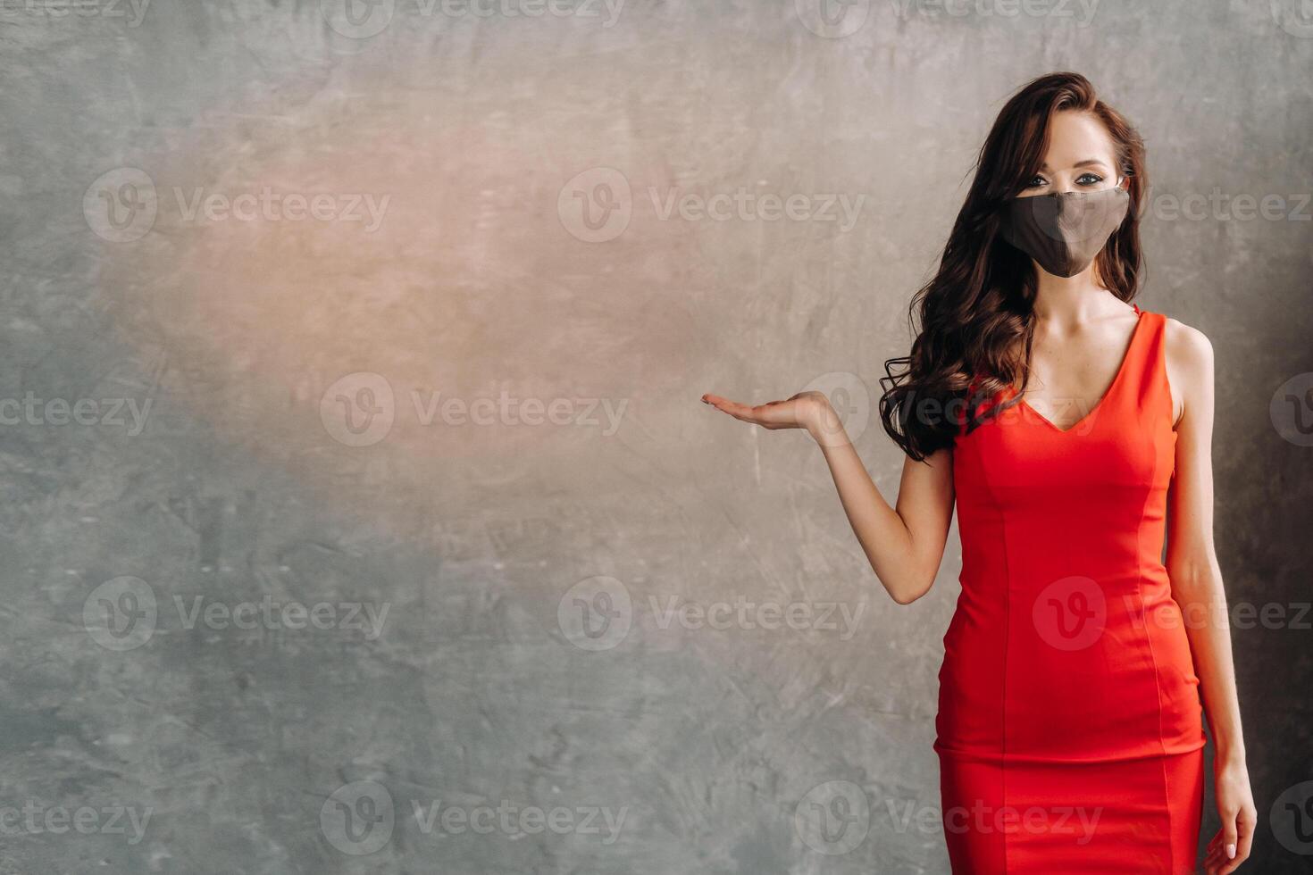 Glamorous girl in a red dress and a protective mask on a vintage background photo
