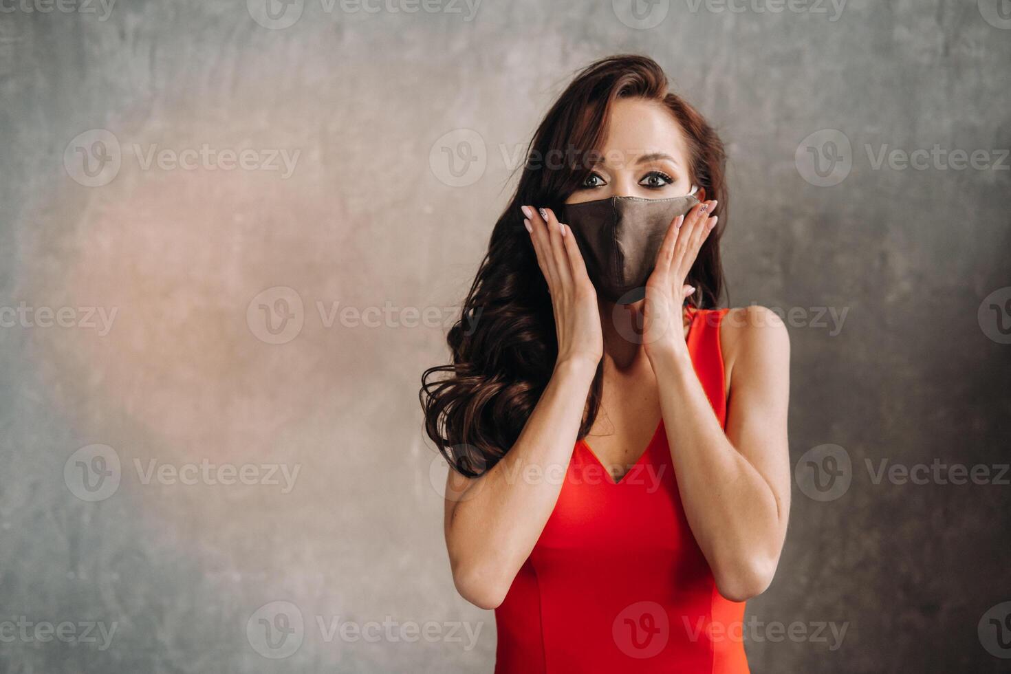 Glamorous girl in a red dress and a protective mask on a vintage background photo