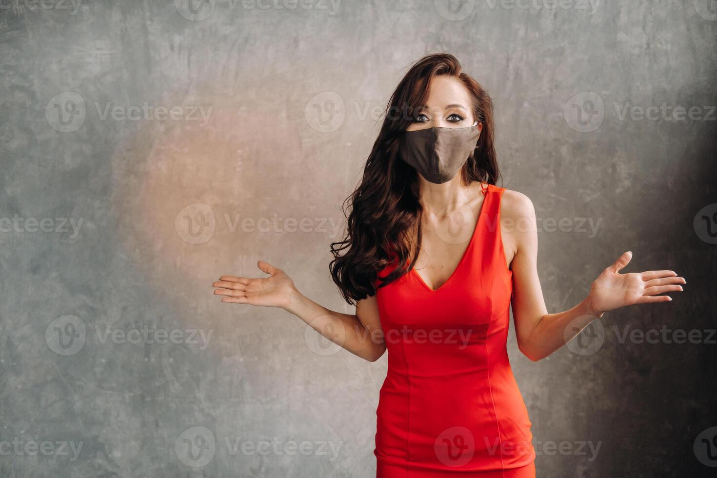 Glamorous girl in a red dress and a protective mask on a vintage background photo