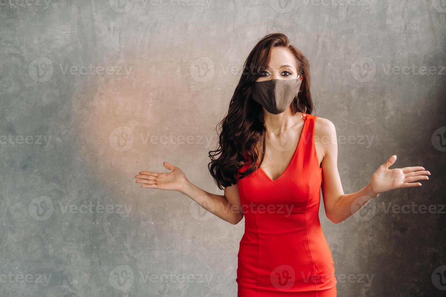 Glamorous girl in a red dress and a protective mask on a vintage background photo