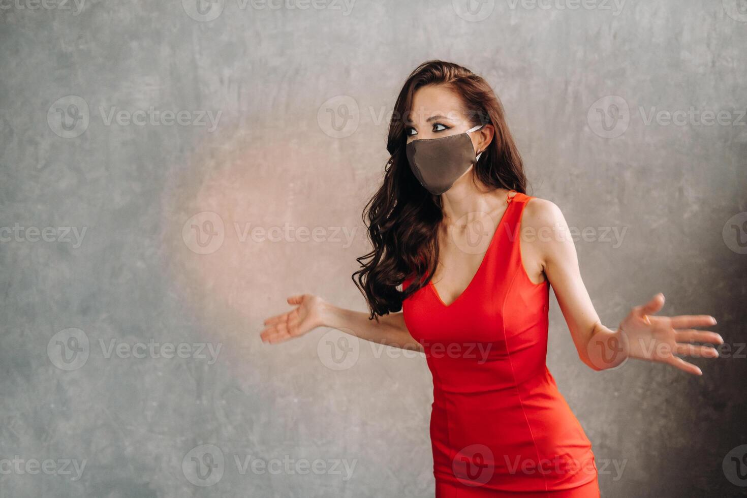 Glamorous girl in a red dress and a protective mask on a vintage background photo