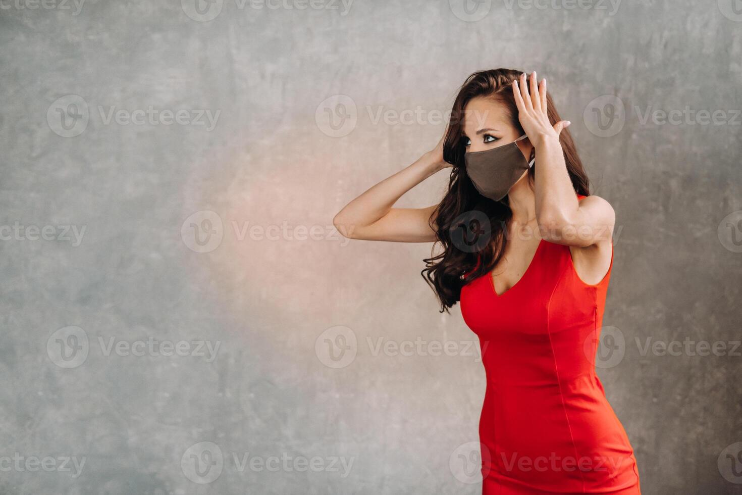 Glamorous girl in a red dress and a protective mask on a vintage background photo