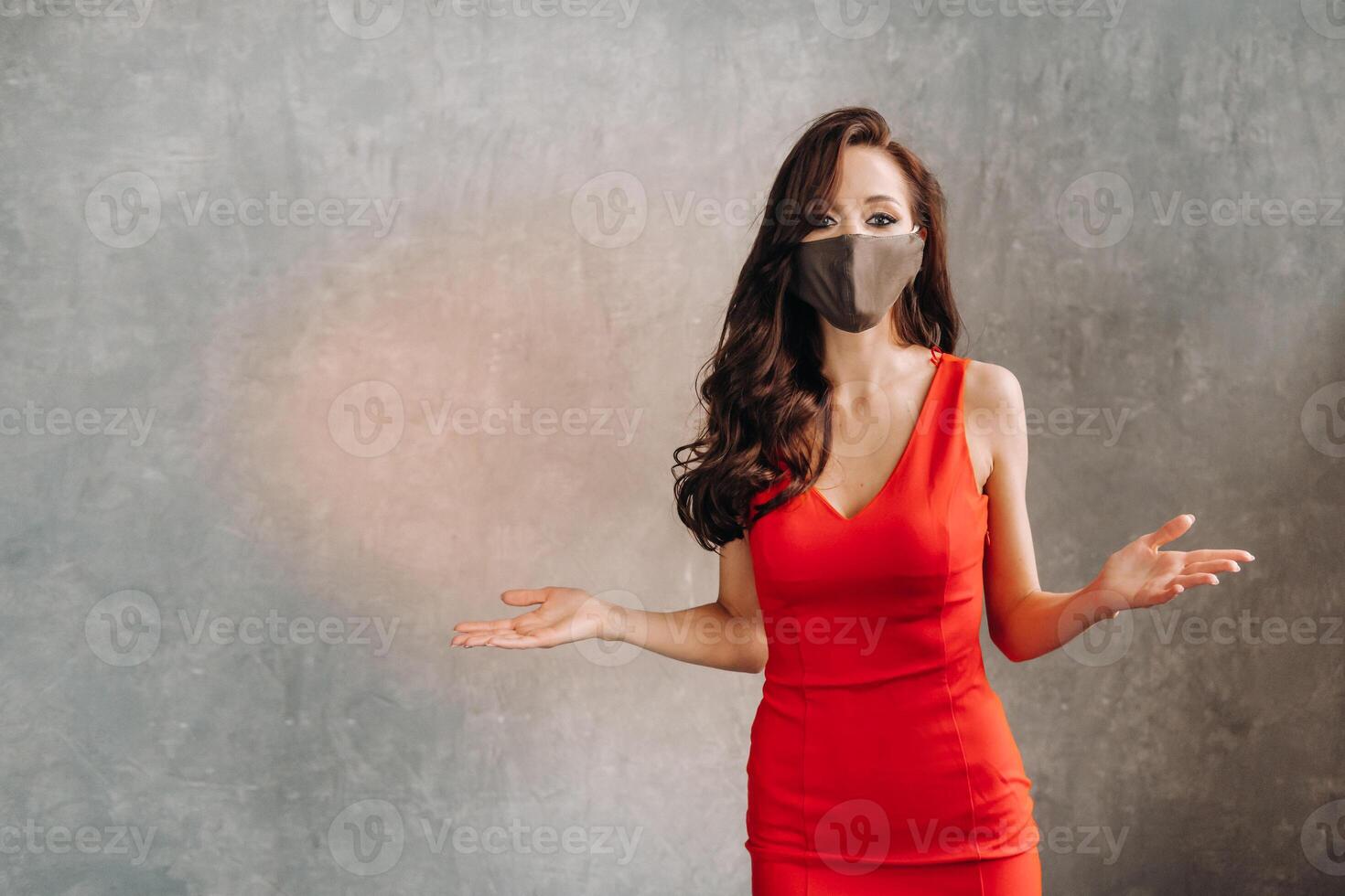 Glamorous girl in a red dress and a protective mask on a vintage background photo