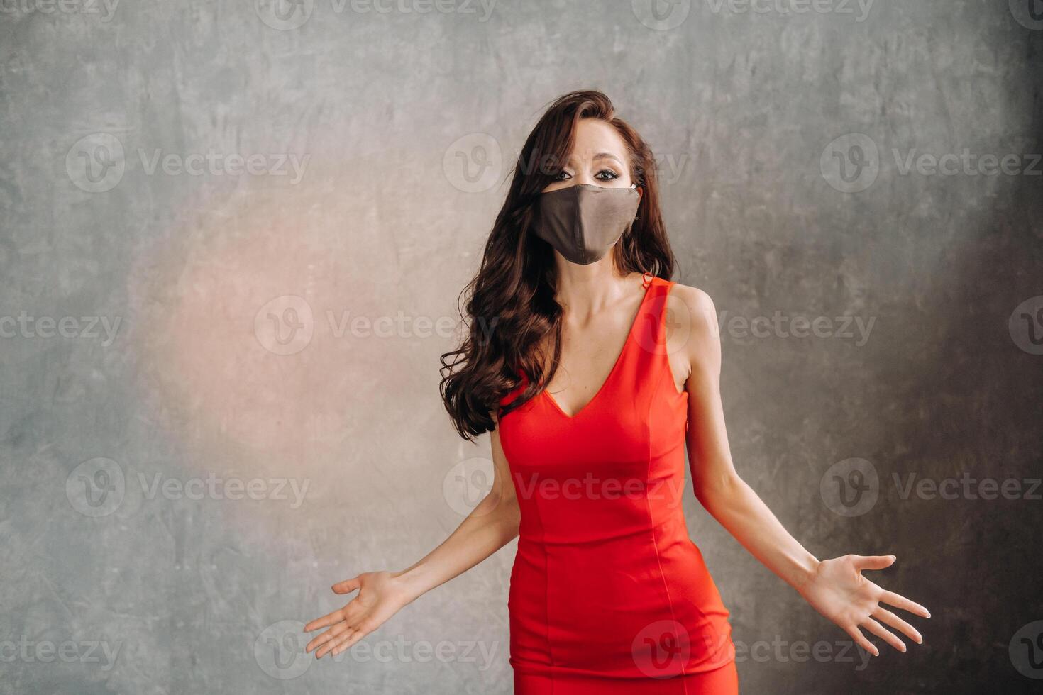 Glamorous girl in a red dress and a protective mask on a vintage background photo