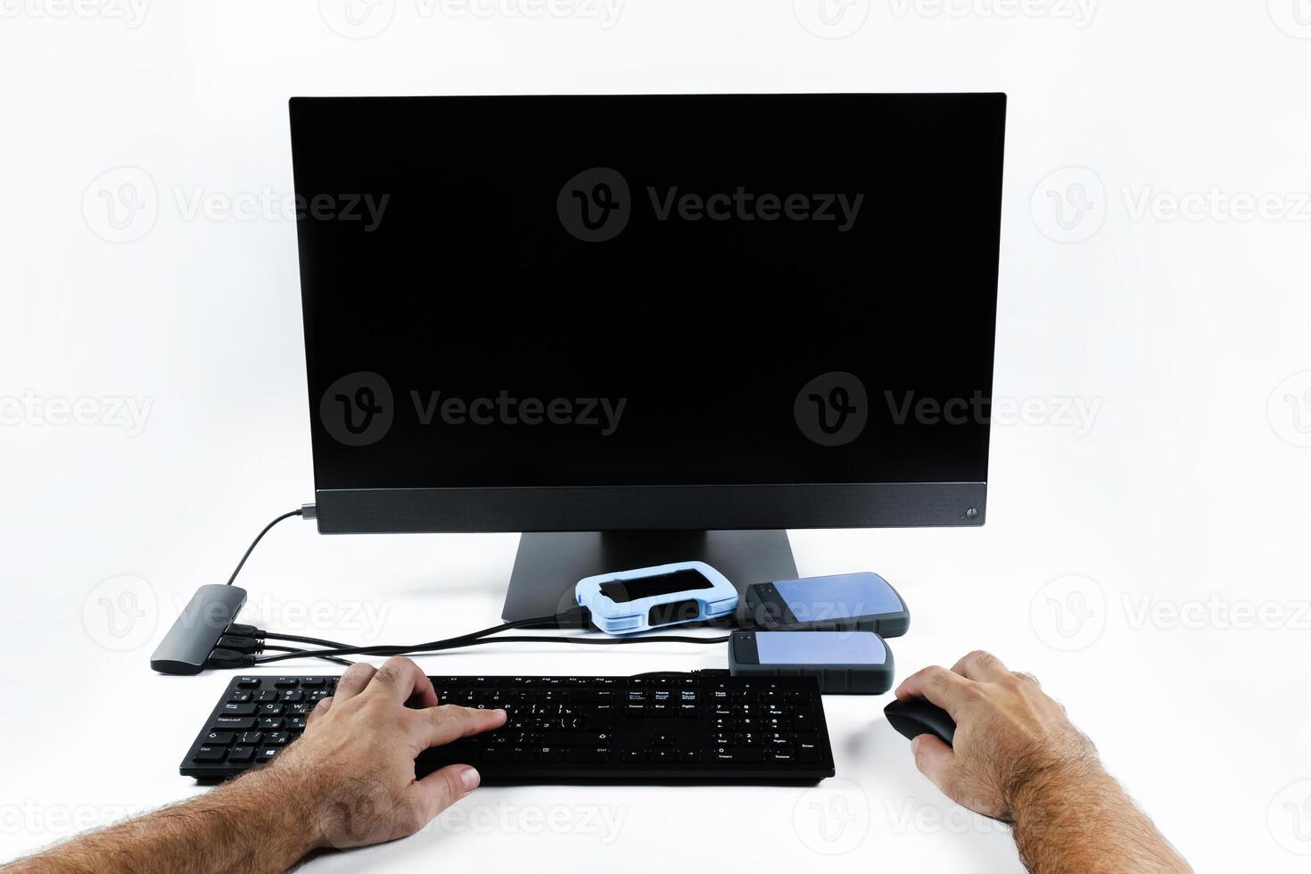 a person works on a computer by pressing the keyboard and holding a mouse on a white background.Monoblock with external hard drives photo