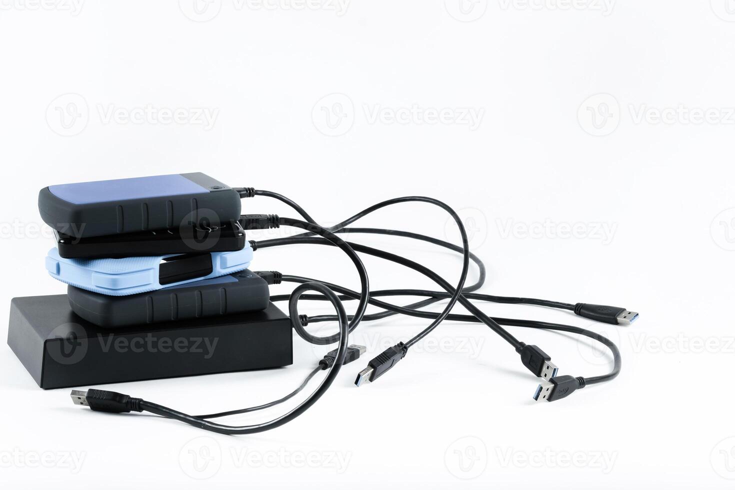 many external hard drives with wires lie on a white background. Hard drives on isolate. photo