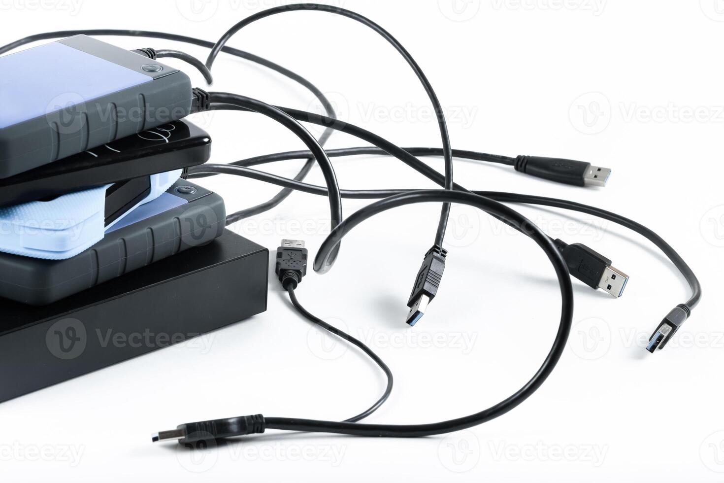 many external hard drives with wires lie on a white background. Hard drives on isolate. photo