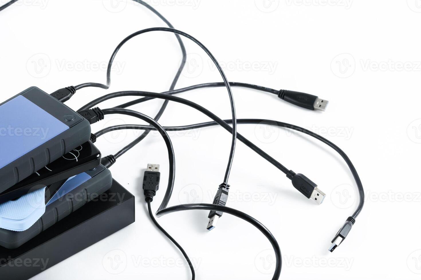 many external hard drives with wires lie on a white background. Hard drives on isolate. photo