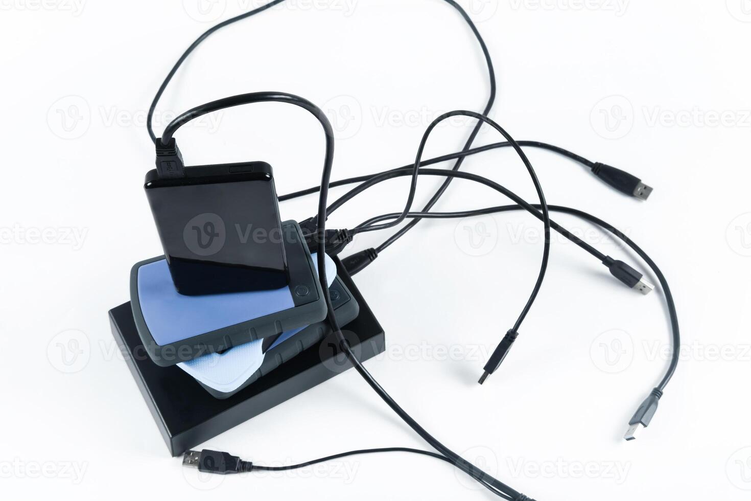many external hard drives with wires lie on a white background. Hard drives on isolate. photo