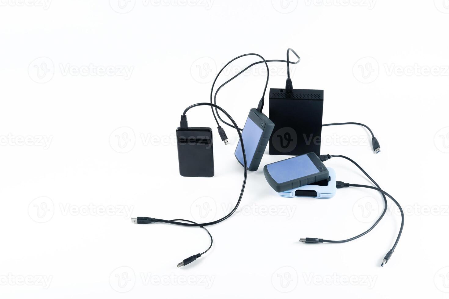 many external hard drives with wires lie on a white background. Hard drives on isolate. photo