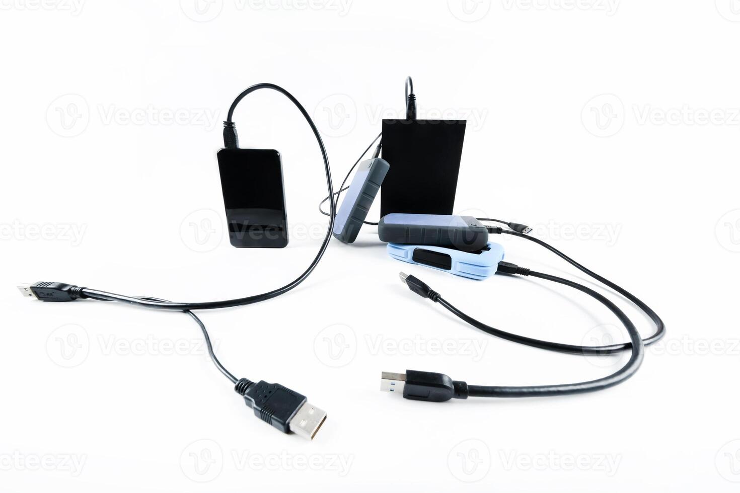 many external hard drives with wires lie on a white background. Hard drives on isolate. photo