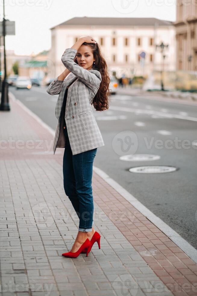 a girl in a jacket and long hair walks through the old city.A beautiful girl smiles.Girl on the road photo
