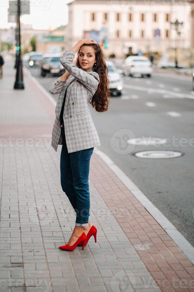 a girl in a jacket and long hair walks through the old city.A beautiful girl smiles.Girl on the road photo