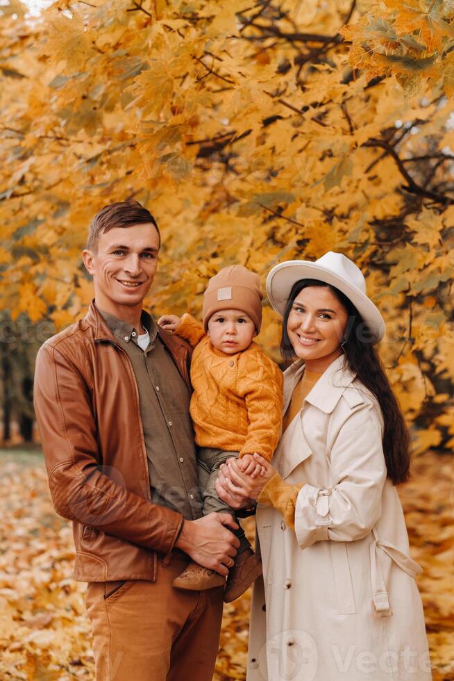 Father and mother with son walking in the autumn Park. A family walks in the Golden autumn in a nature Park. photo