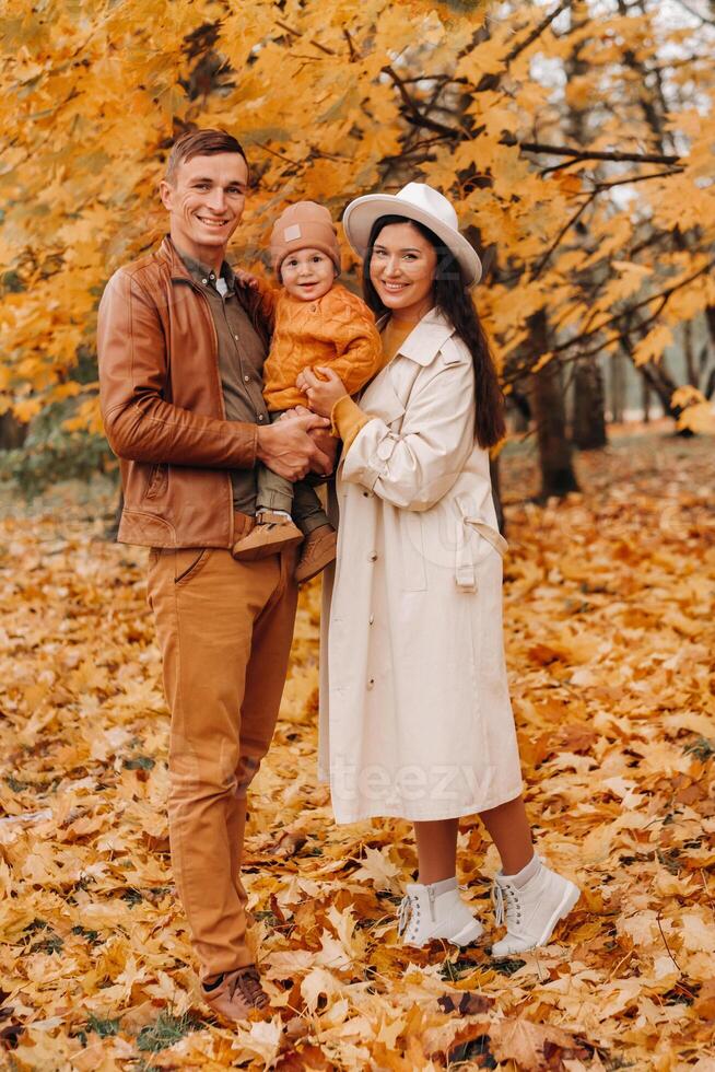Father and mother with son walking in the autumn Park. A family walks in the Golden autumn in a nature Park. photo