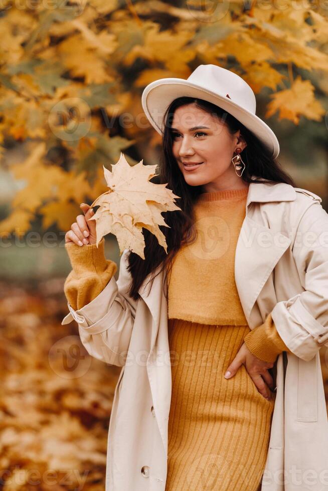 a girl in a white coat and hat smiles in an autumn Park.Portrait of a woman in Golden autumn. photo