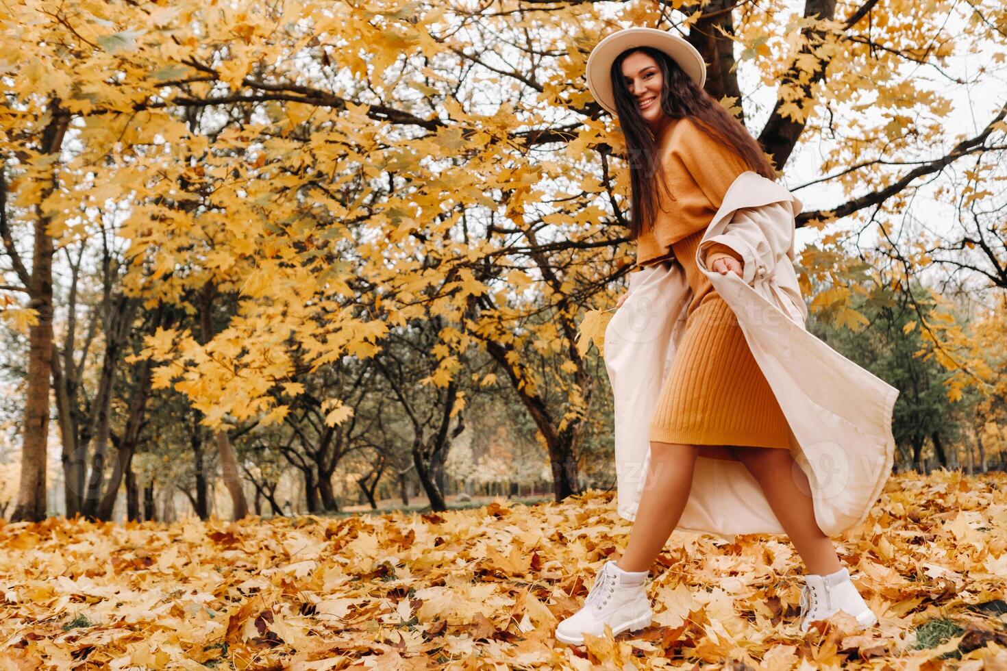 a cheerful girl in a white coat and hat smiles in an autumn Park.portrait of a smiling woman in Golden autumn. photo